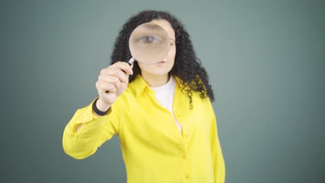 Young-woman-looking-at-camera-with-magnifying-glass.